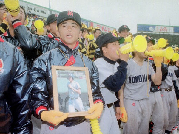 1996年の春のセンバツで、前年に急逝した丹波慎也の遺影を手に応援する横浜高野球部員 photo by Kyodo News