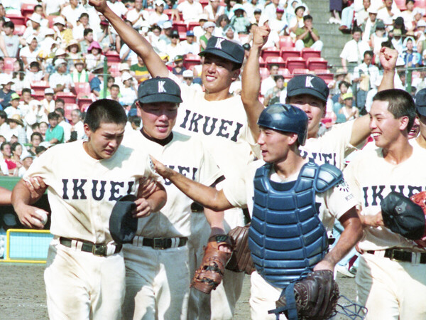 1993年夏の甲子園で初優勝を決め、左脚を負傷した安田聖寛主将（左）を気遣いながら応援席に向かう育英ナイン　photo by Kyodo News