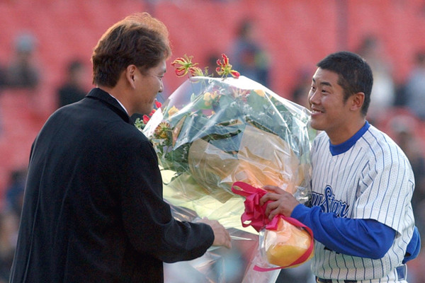 2002年の引退登板後、佐々木主浩（当時マリナーズ）から花束を受け取る野村弘樹
