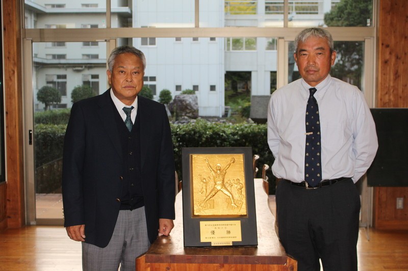 高知商・正木陽総監督（左）と上田修身監督。藤川投手が高知商２年夏に優勝した高知県大会の優勝盾を挟んで