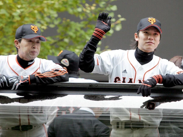 2009年の日本シリーズ優勝パレードでファンに手を振る坂本（右）と、コーチ時代の篠塚　photo by Sankei Visual