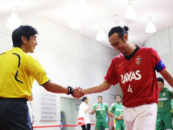 試合後に握手を交わす西村雄一レフェリーと闘莉王　photo by Getty Images