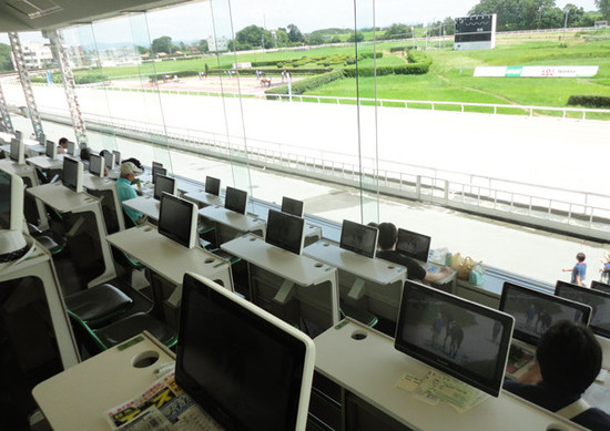 各席にモニターがある「特別観覧席」。笠松競馬場はコースの中にパドックがある（写真左上）