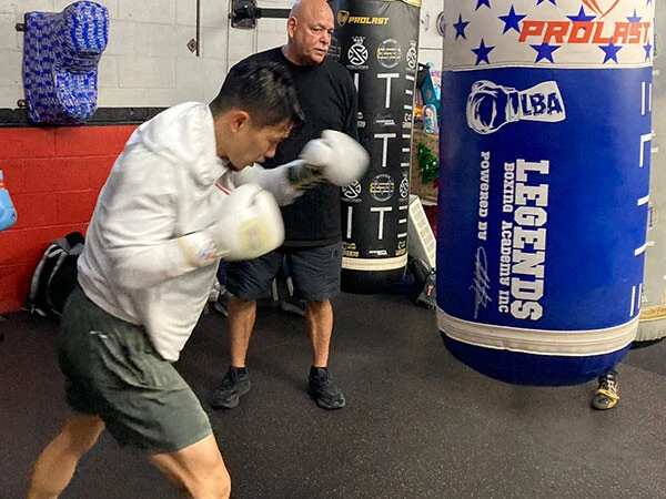 サンドバッグを叩く中谷。後ろはトレーナーのルディ