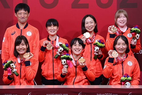 銅メダルを手に笑顔を見せたゴールボール女子チームと市川監督