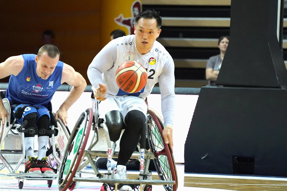 写真:試合中の藤本怜央選手と藤本選手の前で宙を飛ぶボール